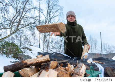 Stacking Firewood Outdoors in Snowy Countryside. Stacking Firewood Outdoors in Snowy Countryside. 136700614