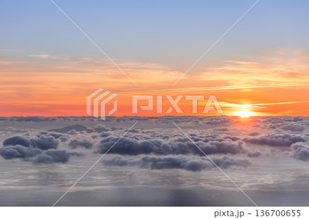 Sunrise above a vast sea of clouds over the Atlantic, soft orange light spreads across calm water 136700655