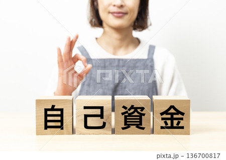 「自己資金」と書かれたブロックとエプロン姿の女性 136700817