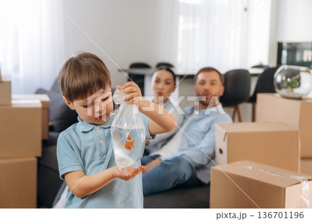 Child is standing and holding fish. Family of husband, wife and son are moving into new house 136701196