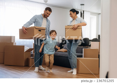 Standing and holding boxes. Family of husband, wife and son are moving into new house 136701205