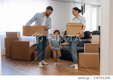 Standing and holding boxes. Family of husband, wife and son are moving into new house 136701206