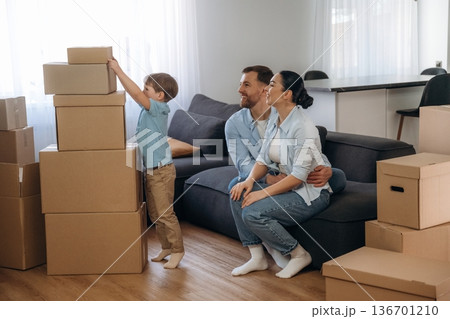Putting small box on top of others. Family of husband, wife and son are moving into new house Putting small box on top of others. Family of husband, wife and son are moving into new house 136701210