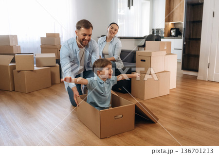 Imagination, flying, sitting in box. Family of husband, wife and son are moving into new house Imagination, flying, sitting in box. Family of husband, wife and son are moving into new house 136701213
