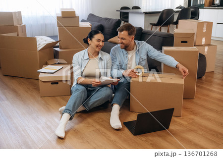 Using scotch to pack the box. Happy couple moved into new house Using scotch to pack the box. Happy couple moved into new house 136701268