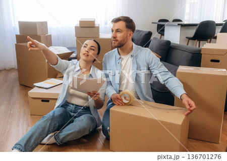 Woman is with documents, man is packing the box. Happy couple moved into new house 136701276