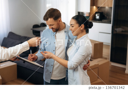 Receiving keys. Couple are buying new house with the help of manager Receiving keys. Couple are buying new house with the help of manager 136701342