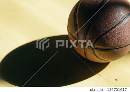 Close up view of basketball ball that is on the ground indoors under sunlight 136701617