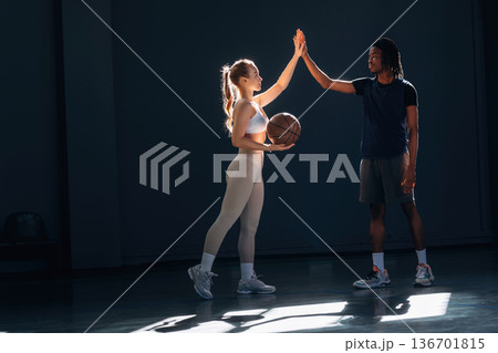 High five hands gesture. Man and woman are standing together, with basketball ball High five hands gesture. Man and woman are standing together, with basketball ball 136701815