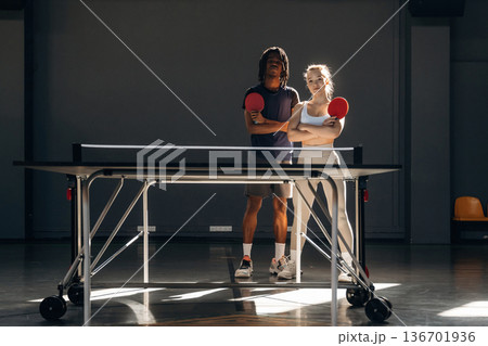 With arms crossed, standing together. Tennis game, man and woman are indoors With arms crossed, standing together. Tennis game, man and woman are indoors 136701936