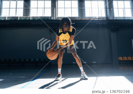 Practicing indoors. Young black man is playing basketball 136702198