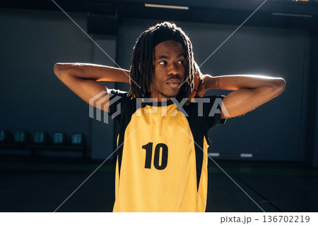 Ball is behind neck. Young black man is playing basketball indoors 136702219