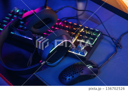 Mouse, keyboard and headphones. Gaming computer is in the dark room with neon lighting Mouse, keyboard and headphones. Gaming computer is in the dark room with neon lighting 136702526
