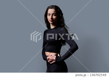 Beautiful athletic young woman with long wavy hair on gray background Beautiful athletic young woman with long wavy hair on gray background 136702549