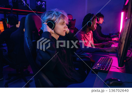 View from the side, sitting. Gamers are playing video game by computers View from the side, sitting. Gamers are playing video game by computers 136702640