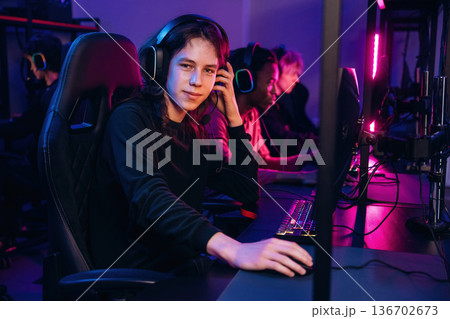 Dude with long hair is sitting. Gamers are playing video game by computers 136702673