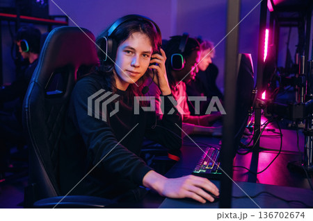 Dude with long hair is sitting. Gamers are playing video game by computers Dude with long hair is sitting. Gamers are playing video game by computers 136702674