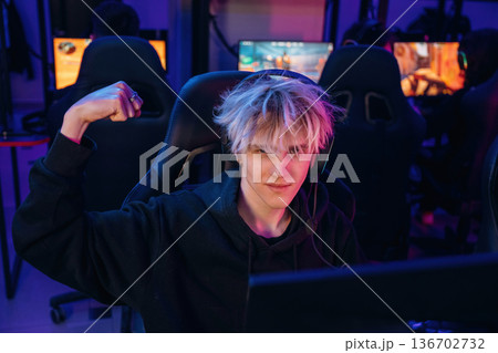Gamer with white hair is sitting by computer indoors Gamer with white hair is sitting by computer indoors 136702732