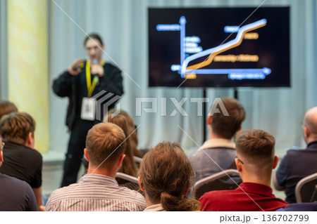 Business conference presentation with speaker and graph on screen for attentive audience Business conference presentation with speaker and graph on screen for attentive audience 136702799