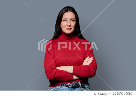 Portrait of beautiful smiling 40 years old woman posing on grey background Portrait of beautiful smiling 40 years old woman posing on grey background 136703550