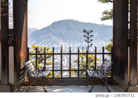 寺院の門と、対に並ぶベンチが作る額縁風景 136703731