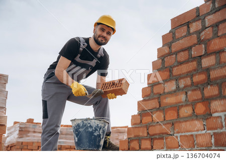 Foundation of wall. Construction worker is at job with bricks outdoors 136704074