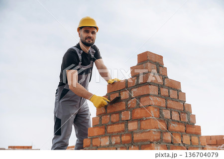 Foundation of wall. Construction worker is at job with bricks outdoors Foundation of wall. Construction worker is at job with bricks outdoors 136704079