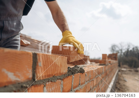 Making the wall. Close up view of construction man that is working with bricks 136704163