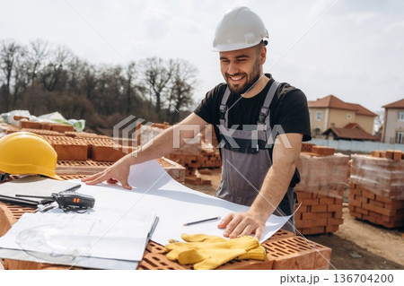 Manager is with project on paper. Construction worker is at job with bricks outdoors Manager is with project on paper. Construction worker is at job with bricks outdoors 136704200