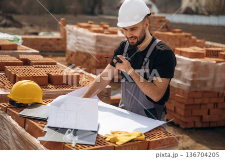 Project plan on the paper. Construction worker is at job with bricks outdoors 136704205