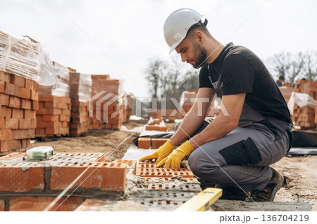 Construction worker is at job with bricks outdoors Construction worker is at job with bricks outdoors 136704219