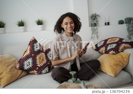 Relaxed Woman Teaching With Smartphone In Cozy Setting Surrounded By Greenery And Soft Cushions Relaxed Woman Teaching With Smartphone In Cozy Setting Surrounded By Greenery And Soft Cushions 136704239