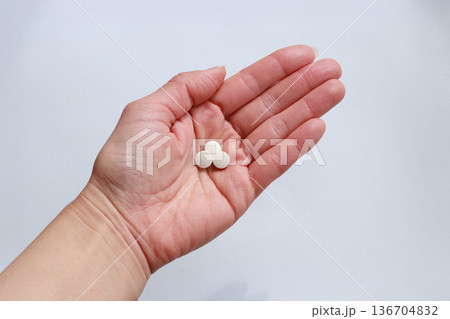 手のひらにのせた白い錠剤 白背景の服薬イメージ・医療と健康管理コンセプト 手のひらにのせた白い錠剤 白背景の服薬イメージ・医療と健康管理コンセプト 136704832