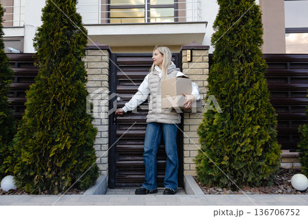 Courier holding parcel and showing thumb up in front of house 136706752