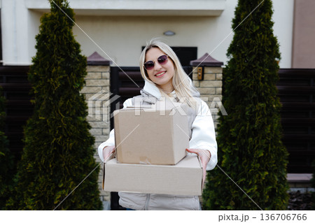 Smiling delivery woman holding a big cardboard box Smiling delivery woman holding a big cardboard box 136706766