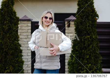Smiling delivery woman holding a big cardboard box 136706767