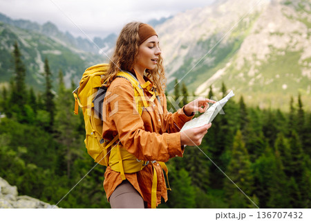 The adventure begins! Beautiful woman traveler with a yellow backpack, holds a map. Vacation concept The adventure begins! Beautiful woman traveler with a yellow backpack, holds a map. Vacation concept 136707432