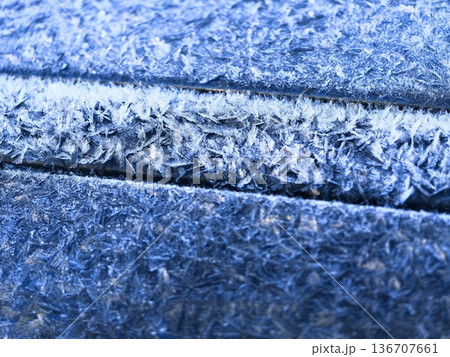 Beautiful macro shot of frost on a blue surface with sharp ice crystals Beautiful macro shot of frost on a blue surface with sharp ice crystals 136707661