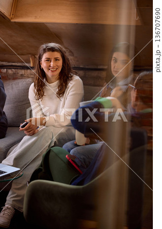 Young professional woman smiling during informal team meeting on sofa. Young professional woman smiling during informal team meeting on sofa. 136707690