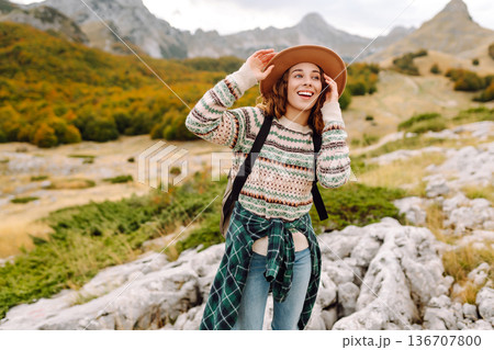 Young woman enjoys sunny afternoon in mountains while sitting on rocks. Tourism. Active lifestyle. Young woman enjoys sunny afternoon in mountains while sitting on rocks. Tourism. Active lifestyle. 136707800