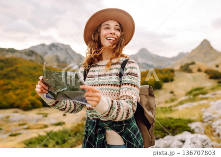 Young woman hiking in autumn landscape with a map. Travel, nature concept. Active lifestyle. 136707803