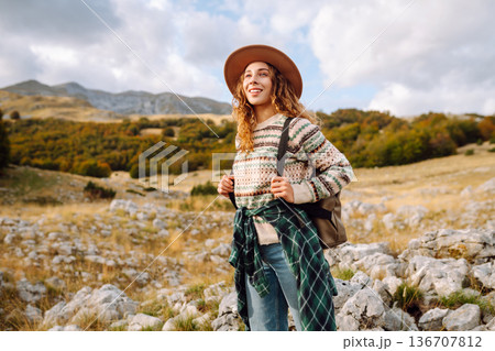 Young woman enjoys sunny afternoon in mountains while sitting on rocks. Tourism. Active lifestyle. Young woman enjoys sunny afternoon in mountains while sitting on rocks. Tourism. Active lifestyle. 136707812