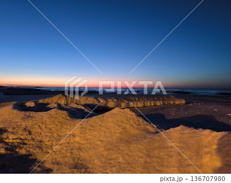 Snowy ice formations and a beautiful sunset on the Baltic Sea coast 136707980