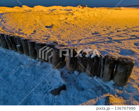 Wooden breakwaters frozen in ice and snow in the Baltic Sea 136707990