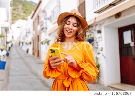 Female traveler in a beautiful yellow dress is sightseeing in European cities. Travel, tourism Female traveler in a beautiful yellow dress is sightseeing in European cities. Travel, tourism 136708067