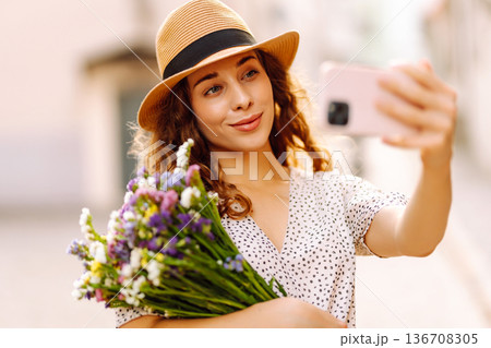 Selfie time. Young woman with a bouquet of wild flowers posing on the street. Fashion style. Selfie time. Young woman with a bouquet of wild flowers posing on the street. Fashion style. 136708305