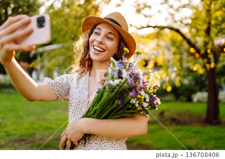 Happy woman strolled through park, carrying bouquet of freshly picked wildflowers. Fashion style. Happy woman strolled through park, carrying bouquet of freshly picked wildflowers. Fashion style. 136708406