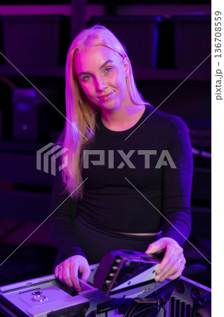 Young woman with blonde hair builds and customizes a gaming computer under purple lighting in a tech setup Young woman with blonde hair builds and customizes a gaming computer under purple lighting in a tech setup 136708559
