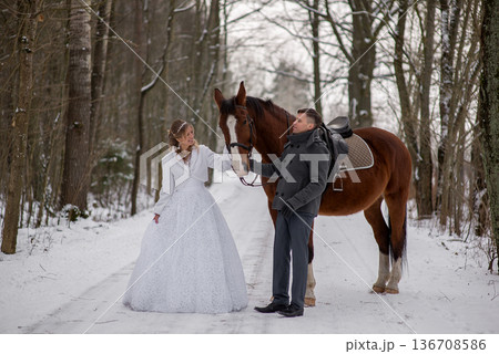 Bride And Groom Holding Horse Reins In Winter Forest 136708586
