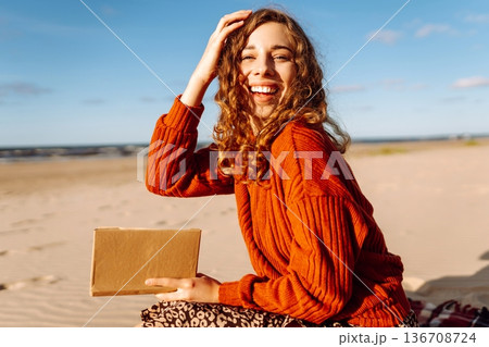 Romantic woman reading book sit on plaid have picnic outdoors on sea. Lifestyle, journey concept. 136708724